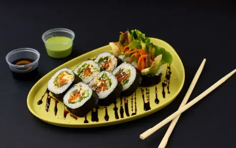 Kimbap-Röllchen mit Gemüse und Fleisch, serviert auf einem gelben Teller mit Sojasauce und Dip. Ein leckeres Kimbap Rezept zum Nachmachen.