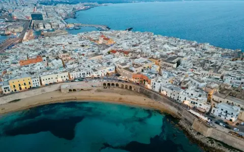 Vista aerea del centro storico di Gallipoli, con case bianche, mare turchese e un arco sul lungomare. Scopri cosa vedere a Gallipoli centro storico.
