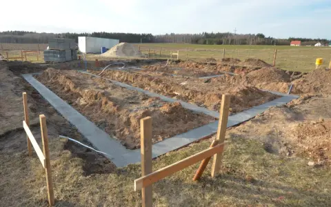Rozpoczęto wylewanie fundamentu pod nowy dom. Wykopano rowy, w których widać świeży beton.
