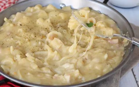 Una padella piena di cremosa pasta con patate, condita con pepe nero. Un piatto confortante e saporito.