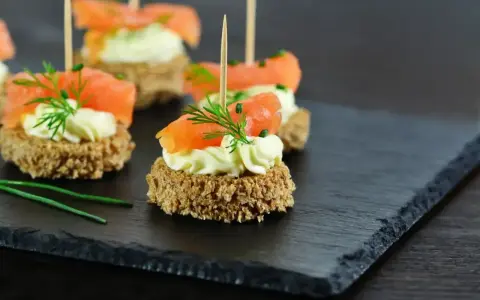 Eleganckie przystawki z łososiem i kremowym serkiem na chrupkim pieczywie, ozdobione koperkiem. Idealne na przyjęcie.