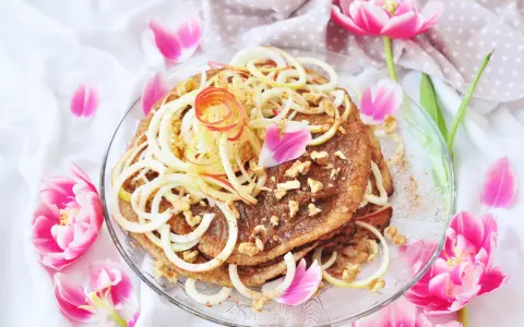 En vacker pannkakstårta med äpple, kanel och valnötter, perfekt för ett pannkakstårta recept. Omgiven av rosa tulpaner.
