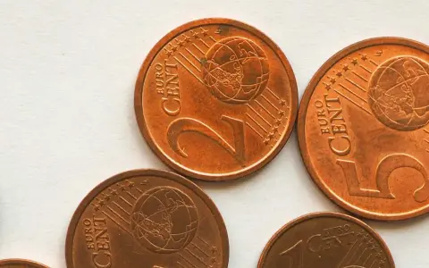 Plusieurs pièces de 2 centimes d'euro, dont une pièce 2 euros rare, sont visibles sur un fond clair.