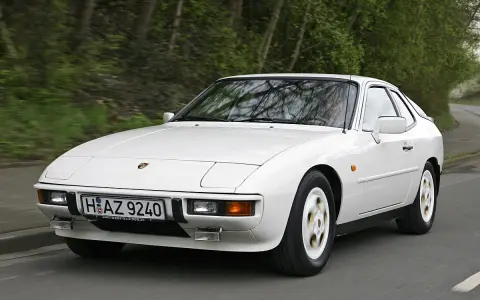 Weißer Porsche 924 fährt auf einer Straße. Der geringe porsche 924 verbrauch macht ihn zu einem sparsamen Klassiker.