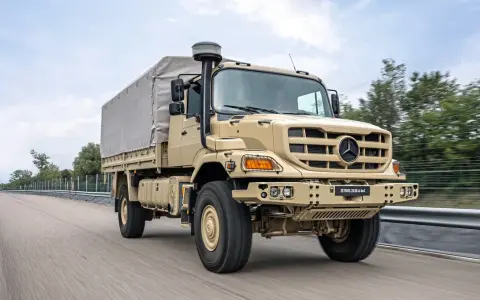 Beżowy Mercedes Zetros 2036 A 4x4 z plandeką jedzie po drodze, gotowy na każde wyzwanie.