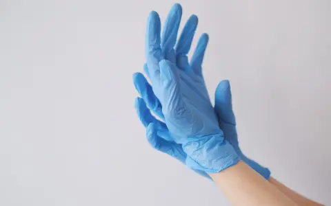 Ręce w niebieskich rękawiczkach nitrylowych, idealnych jako rękawiczki do laboratorium chemicznego.