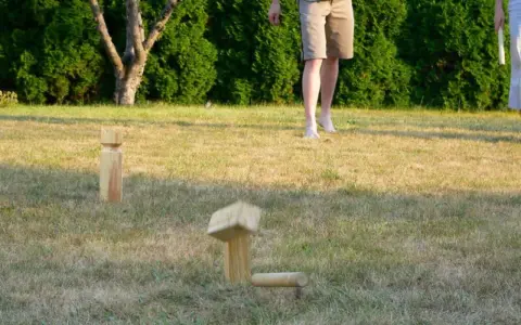 Holzfiguren für Outdoor-Spiele im Gras. Ein Spielstein ist in der Luft, bereit für das nächste Spiel.