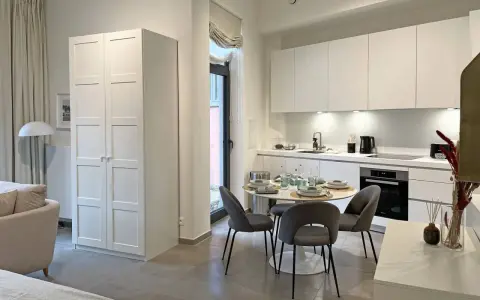 Acogedor cocina salón comedor de 30 m2 con muebles blancos, mesa redonda y sofá.