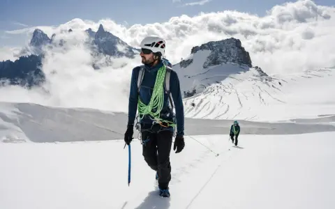 Dwóch alpinistów na ośnieżonym szczycie. Jeden z nich, z czekanem w dłoni, pokazuje, jak dobrać czekan do wspinaczki.