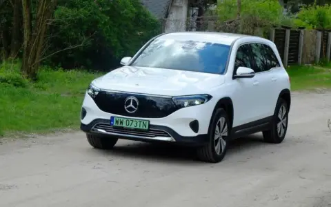 Biały Mercedes EQB na drodze gruntowej, otoczony zielenią.