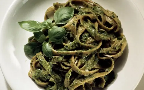 Herzhafte Bandnudeln mit cremiger Pistazien-Pesto-Sauce und frischem Basilikum garniert.