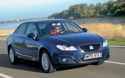 Granatowy Seat Exeo 2.0 TDI jedzie drogą nad rzeką, kierowca w czerwonej kurtce.