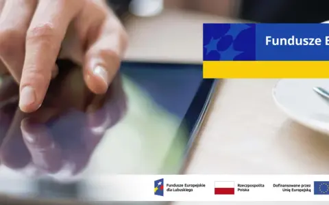 Dłoń dotyka ekranu tabletu, szukając informacji o pożyczki unijne. Na ekranie widnieje napis "Fundusze Europejskie".
