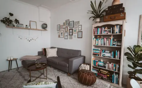 Galeria ścienna z ramkami i girlanda księżycowa nad szarą kanapą. Idealne rozwiązanie, na czym powiesić obraz bez wiercenia.