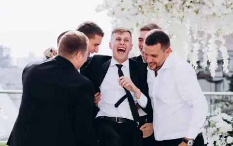 Śmiejący się pan młody otoczony przez przyjaciół. Świetne kawalerski pomysły na wspólne chwile przed ślubem.