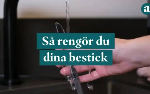 En hand håller ett bestick under rinnande vatten. Texten "Så rengör du dina bestick" visas.