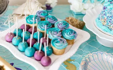 Söta cupcakes och cake pops i lila och turkost, perfekta att köpa till babyshower. Havstema med pärlor och snäckskalsformade tallrikar.