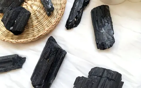 Cristales de turmalina negra, algunos en una cesta de mimbre, listos para atraer el amor y la protección.