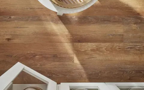 Drewnopodobne panele laminowane czy winylowe na podłodze, z białymi meblami i fragmentem okrągłego stolika.