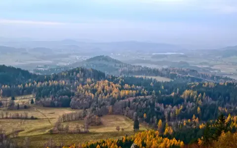 Jesienny krajobraz Gór Izerskich. Złote i zielone lasy, pola i mgliste wzgórza tworzą malownicze szlaki.