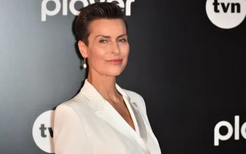 Danuta Stenka w białej kreacji, gwiazda filmów, seriali i programów, na tle logo TVN i Playera.