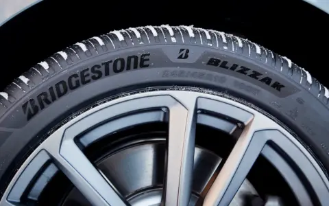 Opony zimowe Bridgestone Blizzak na feldze, pokryte śniegiem. Wiele pozytywnych opony Bridgestone opinie potwierdza ich jakość.