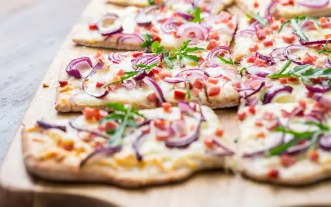 Flammkuchen mit Zwiebeln, Speck und Rucola. Ein köstlicher Flammkuchen Belag, der Appetit macht.