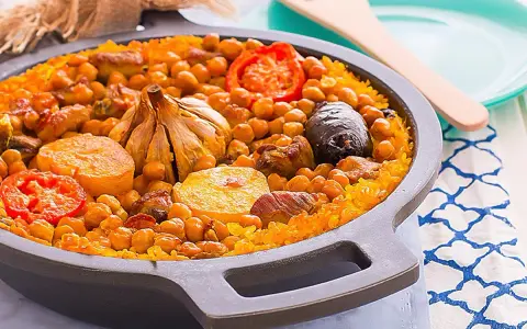 Arroz al horno valenciano con garbanzos, tomate, patata, ajo y morcilla en una paellera.