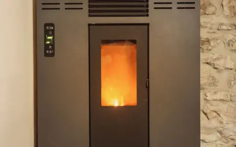 Stufa a pellet con fiamma viva visibile. Il pannello di controllo mostra "19.5°". La distanza candeletta stufa pellet è ottimale per l'accensione.