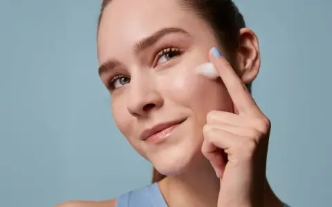 Donna applica schiuma sul viso, un gesto essenziale per la skincare routine mattina e sera. Pelle luminosa e curata.