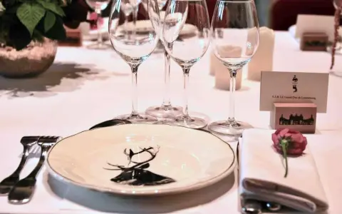 Un élégant dressage à la française pour un dîner de gala, avec une assiette ornée d'un cerf, des verres à pied et une carte de visite pour le Grand-Duc de Luxembourg.