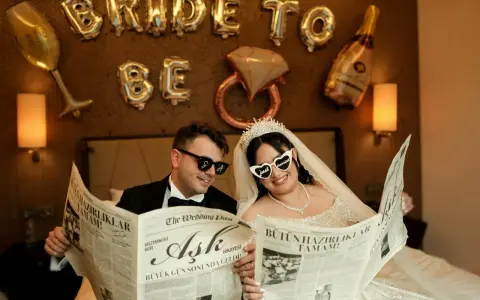 Para młoda czyta gazetę z nagłówkiem "Plan wesela". Balony w kształcie liter "BRIDE TO BE" tworzą tło.