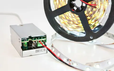 Zasilacz do taśmy LED 5m. Zasilacz impulsowy z zielonym złączem i czerwoną diodą. Rolka taśmy LED z białymi diodami.