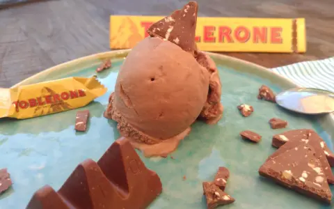 Schokoladeneis mit Toblerone-Stücken und einer ganzen Toblerone-Tafel auf einem Teller.