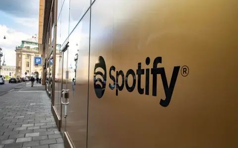 Spotify-logotypen på en guldfärgad fasad. En gata med bilar och människor syns i bakgrunden, vilket antyder att går Spotify med vinst.