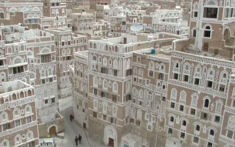 Ein malerisches arabisches Haus mit kunstvollen weißen Verzierungen und vielen Fenstern, eingebettet in eine Stadt mit ähnlicher Architektur.