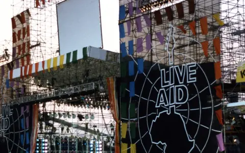Scena Live Aid w Polsce, ozdobiona kolorowymi flagami i wielkim logo.