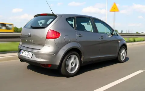 Szary Seat Altea XL jedzie autostradą. W tle widać żółty autobus i znak ostrzegawczy.