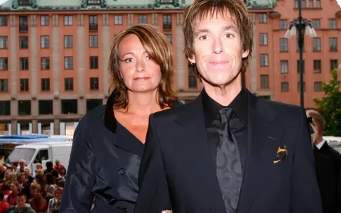 Gessle, ung och stilig, poserar med en kvinna framför en byggnad i Stockholm.