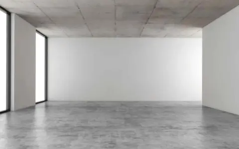 Espacio minimalista con paredes blancas, techo de hormigón y suelo de **cemento pulido** que refleja la luz.