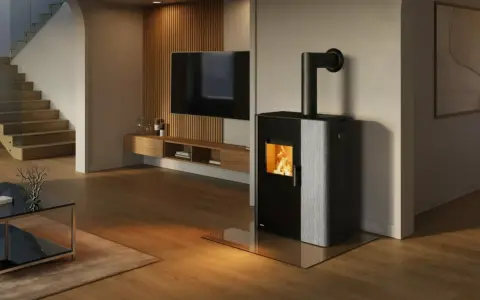 Estufa mixta pellets y leña canalizable, con fuego encendido, en un salón moderno con escaleras y TV.