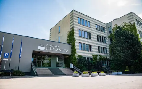 Akademia Humanitas w Katowicach, gdzie można studiować psychologię. Budynek z zielenią i parkingiem.