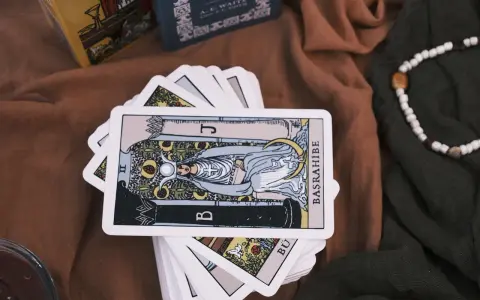 Karty tarota ułożone na brązowym materiale. Jedna karta, przedstawiająca postać z księżycem i owocami, jest na wierzchu. To idealny obrazek na **tarot na tydzień**.