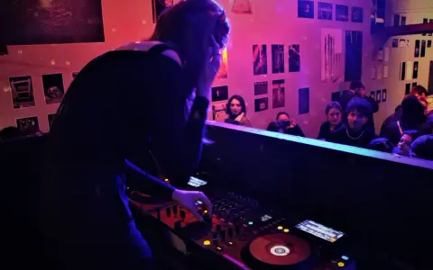 Une dj femme aux platines, ambiançant une foule dans un club.