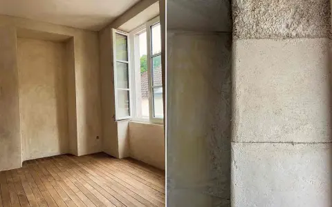Intérieur d'une pièce aux murs enduits de chaux liège, avec un parquet en bois brut. Gros plan sur la texture rugueuse d'un mur en chaux liège.