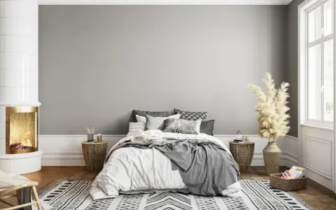 Dormitorio acogedor con chimenea encendida. El gris claro de la pared combina con blanco, negro y tonos tierra, creando un ambiente sereno.