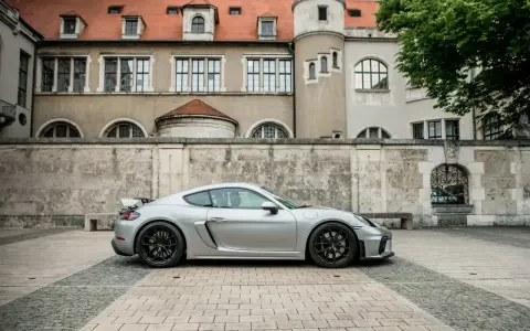 Silberner Porsche GT4 vor historischer Kulisse. Die technischen Daten dieses Sportwagens sind beeindruckend.