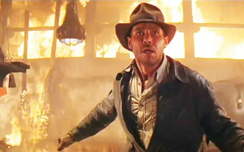 Indiana Jones in un edificio in fiamme, un momento iconico di film azione e avventura.