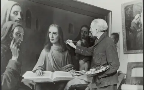 Giuliano Ruffini, artiste peintre, retouche une toile représentant des figures religieuses. Il tient pinceaux et palette.