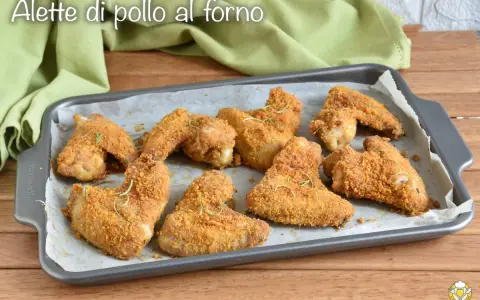 Alette di pollo al forno dorate e croccanti, guarnite con rosmarino fresco, pronte per essere gustate.